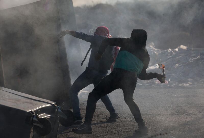 A Palestinian protester throws a Molotov cocktail during clashes with Israeli troops during demonstration in against the Israeli offensive on Gaza, at checkpoint Beit El near the West Bank city of Ramallah. AP Photo