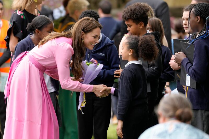 The princess shakes hands with children before the picnic. AP