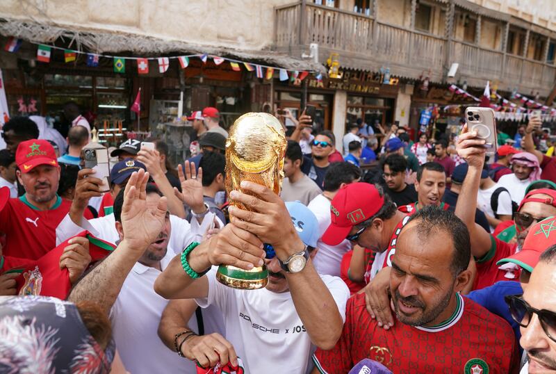 Fans with a replica World Cup Trophy in the Souq Waqif area of Doha. PA
