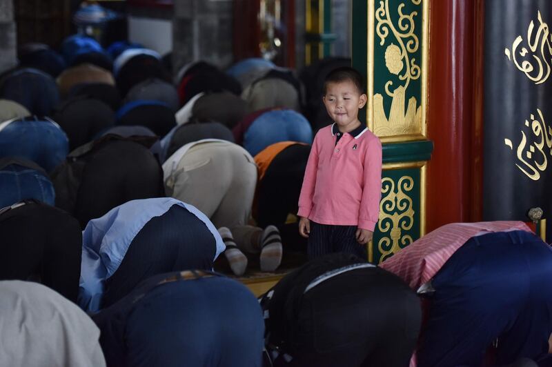 A young boy watches as Muslim men pray on the first Friday of Ramadan at a mosque in Beijing.   AFP