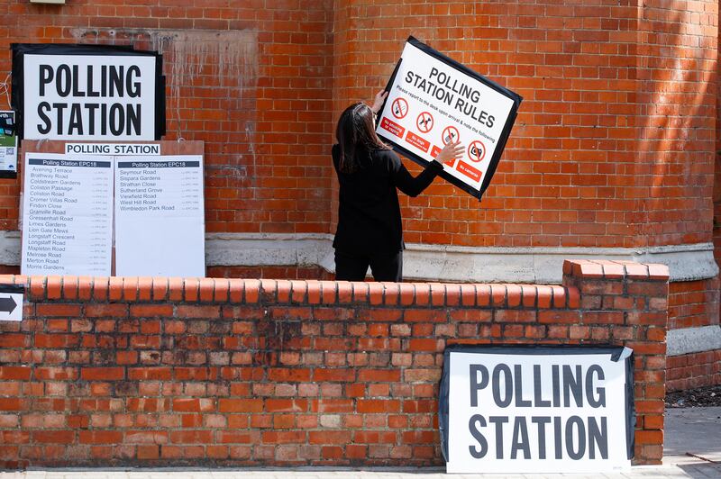 A woman attaches a sign on the wall of a polling station in London. Reuters