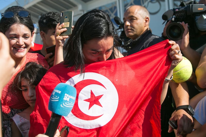 Jabeur kisses the Tunisian flag at Tunis airport. Tunisians have remained enthralled with the tennis star, celebrating her presence in the prestigious Wimbledon final despite her loss. AP