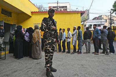 A security officer stands guard as people wait in a queue to cast their their votes for the state elections in Bhopal, Madhya Pradesh. AP Photo