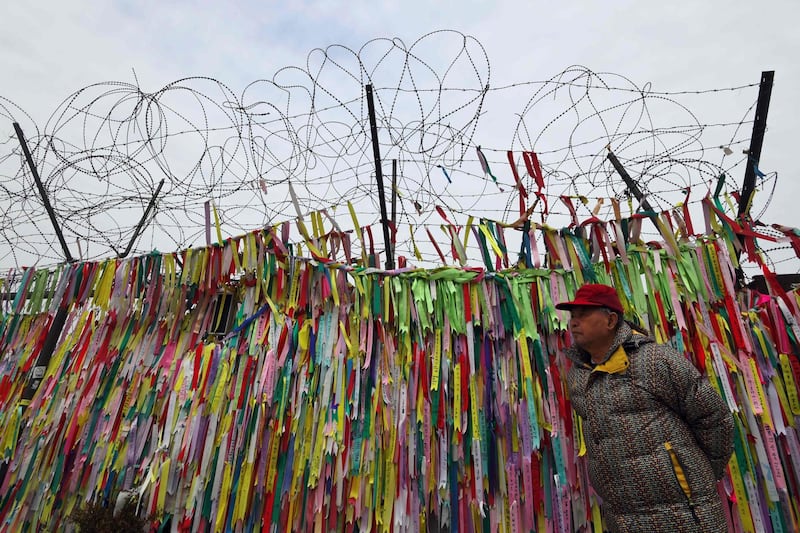 TOPSHOT - A man walks past a military fence covered with ribbons calling for peace and reunification at the Imjingak peace park near the Demilitarized Zone (DMZ) dividing the two Koreas at the border city of Paju on January 8, 2018.
The two Koreas agreed last week to hold their first official dialogue in more than two years and will meet on January 9 at the border truce village of Panmunjom. / AFP PHOTO / JUNG Yeon-Je