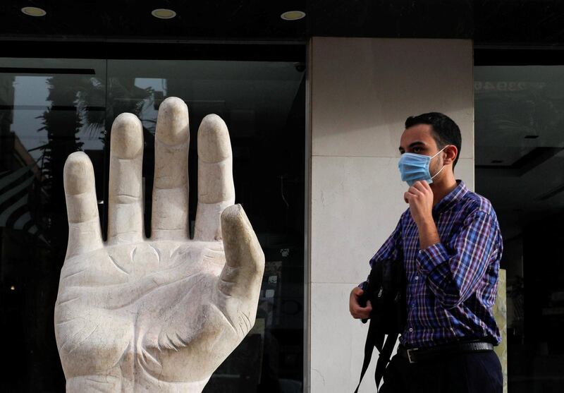 A man wearing a protective face mask walks near a granite symbol hand of peace, amid concerns over the coronavirus disease. Reuters
