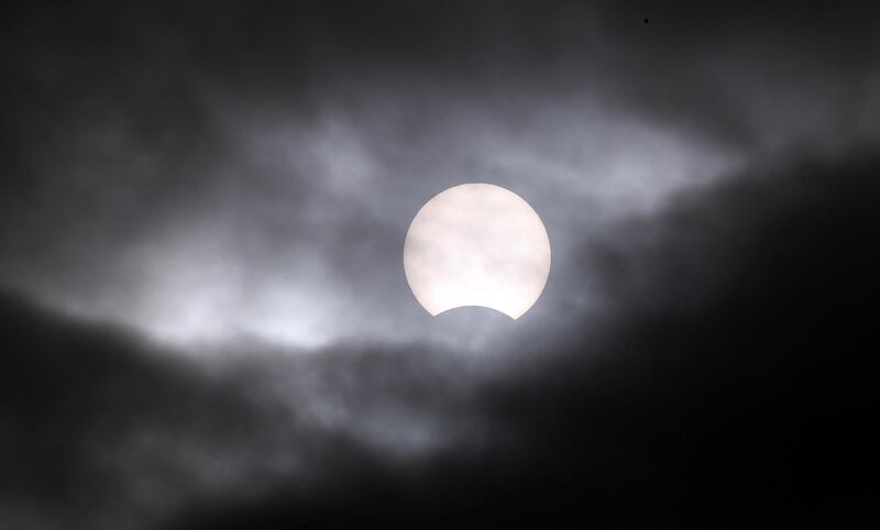 A partial solar eclipse is visible through clouds in Seoul, South Korea.  EPA