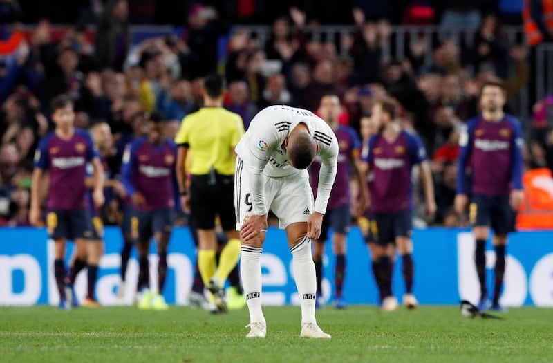 Real Madrid's Karim Benzema looks dejected as Barcelona's Arturo Vidal celebrates scoring their fifth goal with team-mates. Reuters