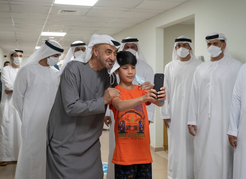 Sheikh Mohamed bin Zayed Al Nahyan, Crown Prince of Abu Dhabi and Deputy Supreme Commander of the UAE Armed Forces, left, stands for a photograph with a young Afghan boy at Emirates Humanitarian City. Photo: Ministry of Presidential Affairs.