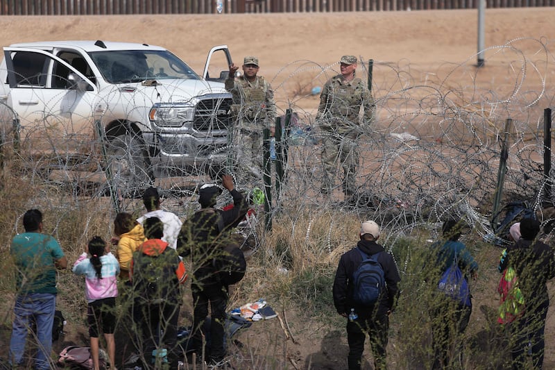 Texas National Guard agents prevent migrants from Venezuela from crossing a barbed wire fence at the El Paso  border, after they crossed the Rio Grande from Mexico. AFP