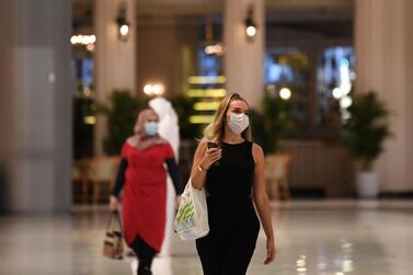 Women wearing masks for protection against the coronavirus, walk in the Mall of Dubai on April 28, 2020, after the shopping centre was reopened as part of moves in the Gulf emirate to ease lockdown restrictions imposed last month to prevent the spread of the COVID-19 illness. / AFP / Karim SAHIB