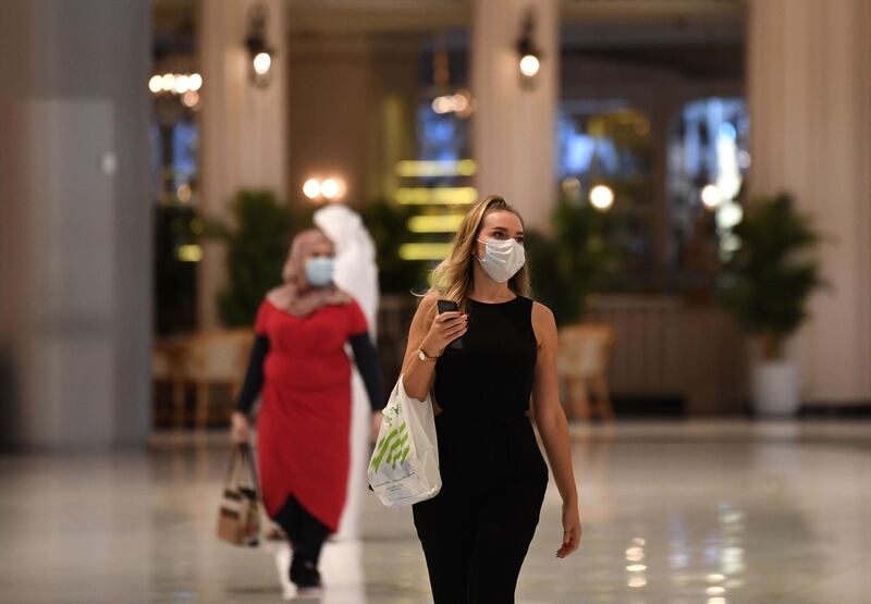 Women wearing masks for protection against the coronavirus, walk in the Mall of Dubai on April 28, 2020, after the shopping centre was reopened as part of moves in the Gulf emirate to ease lockdown restrictions imposed last month to prevent the spread of the COVID-19 illness.  / AFP / Karim SAHIB
