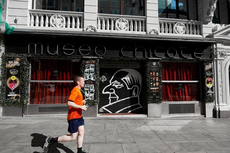 MADRID, SPAIN - SEPTEMBER 29: A man runs through the door of the closed Museo Chicote restaurant on September 29, 2020 in Madrid, Spain. The iconic street of Gran Via, the busiest in Spain and the third in Europe, hosts a lot of theatres, cinemas, souvenir stores and restaurants. Many of them are still closed, more than six months after the coronavirus outbreak hit Madrid.  (Photo by Carlos Alvarez/Getty Images)