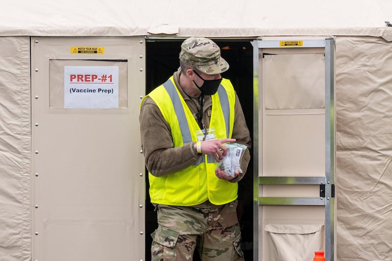 A member of the California National Guard carries syringes filled with doses of the Pfizer-BioNTech Covid-19 vaccine at mass vaccination site at the Oakland Coliseum in Oakland, California. Bloomberg