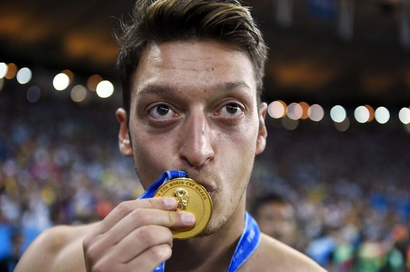 (FILES) In this file photo taken on July 13, 2014, Germany's midfielder Mesut Ozil kisses his medal after Germany won the 2014 FIFA World Cup final football match between Germany and Argentina 1-0 following extra-time at the Maracana Stadium in Rio de Janeiro, Brazil. Mesut Ozil's decision to quit playing for the German national football team Die Mannschaft unleashed on July 23, 2018 a racism storm in Germany, but earned the applause of Ankara with a Turkish minister hailing "a goal against the virus of fascism". / AFP / Fabrice COFFRINI
