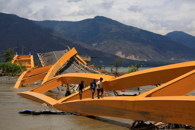 People walk on a broken bridge after it was hit by an earthquake and tsunami last week in Palu, Sulawesi island, Indonesia. Reuters