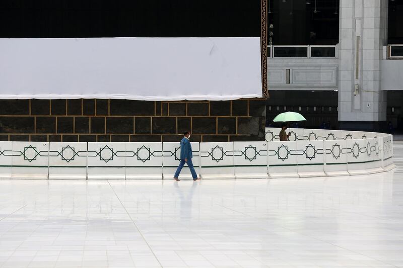 A worker, mask-clad due to the COVID-19 coronavirus pandemic, at the the Grand Mosque complex in Saudi Arabia's holy city of Mecca walks past the Kaaba, Islam's holiest shrine, at the centre of the complex, ahead of the annual Hajj pilgrimage season.  AFP