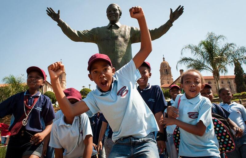 South African children cheer and pose beside the Nelson Mandela statue at the Union Buildings in Pretoria. Stefan Heunis / AFP Photo