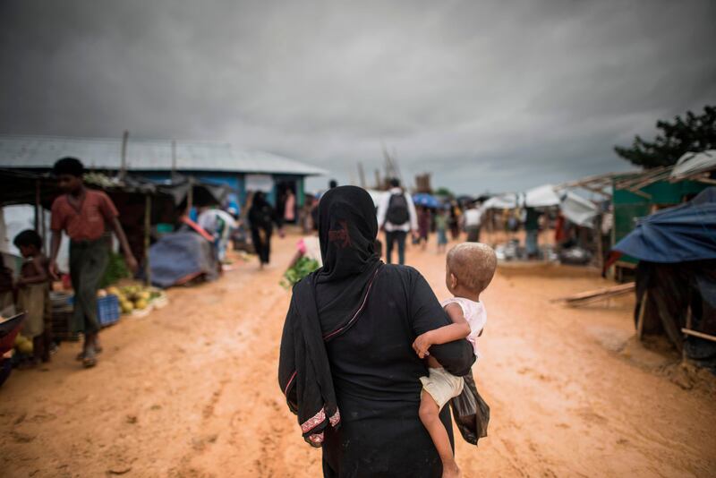A Rohingya Muslim refugee carries a child through Kutupalong refugee camp in the Bangladeshi district of Ukhia on September 28, 2017.
Representatives of UN agencies will be permitted to visit Rakhine state in Myanmar on September 28 for the first time since the start of a massive exodus of minority Rohingya Muslims. The United Nations has been demanding access since its humanitarian organizations were forced to pull out of Rakhine when Myanmar's military launched operations against Rohingya rebels in late August, causing hundreds of thousands to flee into neighboring Bangladesh. / AFP PHOTO / FRED DUFOUR