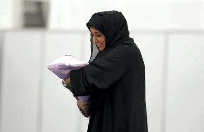 RAK,  UNITED ARAB EMIRATES , OCTOBER 5 – 2019 :- One of the staff holding baby so that couple cast their vote for the FNC election at the HCT Ras Al Khaimah Women’s College in Ras Al Khaimah. ( Pawan Singh / The National ) For News. Story by Ruba