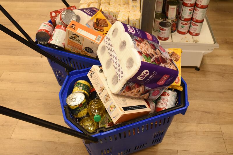 People fill their baskets with essential items from the food bank.