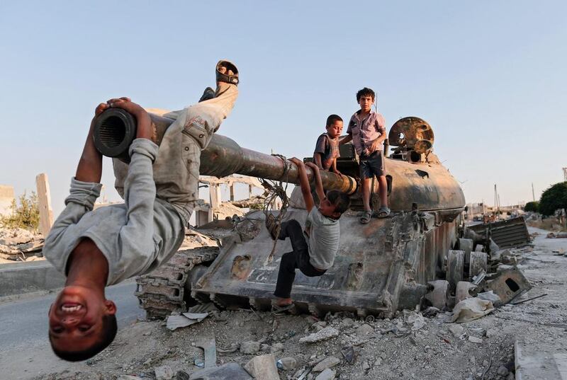 Syrian children play on a destroyed tank south of Kobane, Syria.  Sedat Suna / EPA