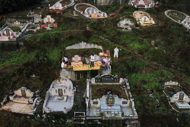 A Chinese-Malaysian family, with offerings of food and paper money, praying at the grave of an ancestor on the eve of the Qingming festival, known as ‘Tomb Sweeping Day’, in Karak, Malaysia. AFP