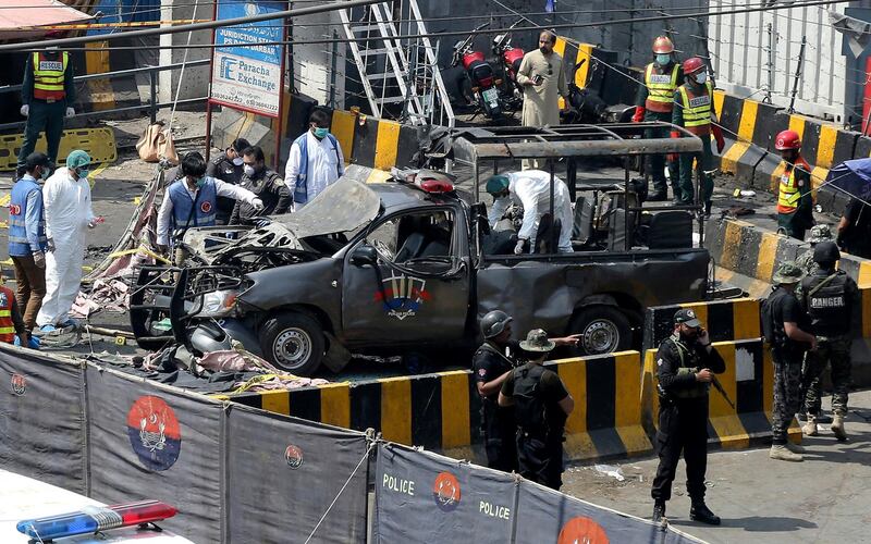Security personnel surround a damaged police van. AP Photo