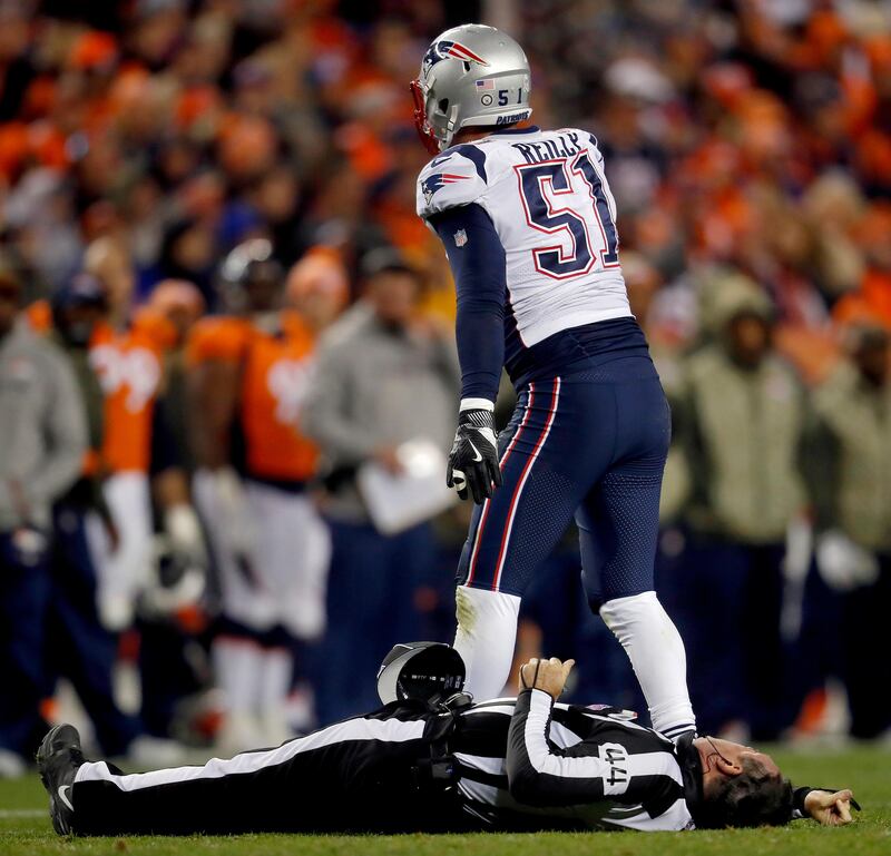 New England Patriots linebacker Trevor Reilly signals for help accidentally knocking down umpire Jeff Rice. David Zalubowski / AP Photo