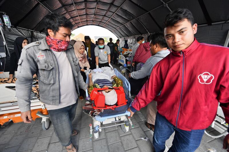 An injured earthquake victim is stretchered through a makeshift ward set up outside the Moh. Ruslan hospital in Mataram on the Indonesian island of Lombok. AFP