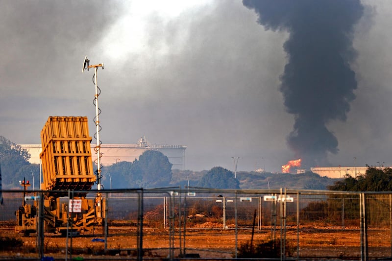 An Iron Dome aerial defence system battery is seen in the foreground as fire rages at Ashkelon's refinery, which was hit by Hamas rockets the previous day, in the southern Israeli city. AFP