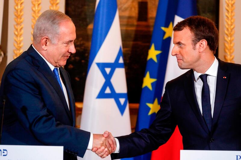 Israeli Prime Minister Benjamin Netanyahu (L) and French President Emmanuel Macron shake hands during a joint news conference following their meeting at the Elysee Palace in Paris on December 10, 2017.
French President Emmanuel Macron urged Israeli Prime Minister Benjamin Netanyahu to freeze Israeli settlement building during their talks in Paris on December 10. / AFP PHOTO / POOL / PHILIPPE WOJAZER