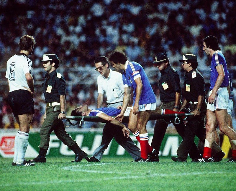 French defender Patrick Battiston evacuated on a stretcher eyed by French forward Michel Platini after colliding with German goalkeeper Harald Schumacher during the World Cup semi-final match France vs Germany. (AFP PHOTO)