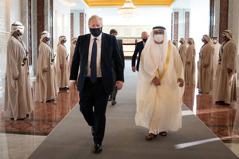 Mr Johnson inspects a guard of honour as he walks with Anwar Gargash, diplomatic adviser to the UAE President. Reuters