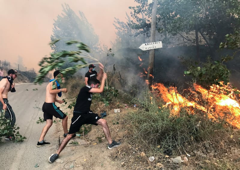 Residents use branches in a desperate effort to halt the flames in the mountainous Tizi Ouzou area, east of Algiers.