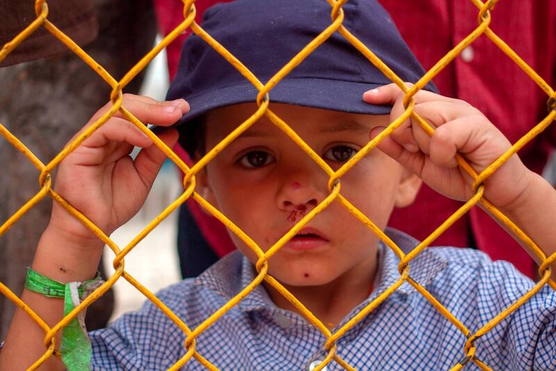 A Honduran migrant boy looks thorugh the fence of a warehouse used as shelter in Piedras Negras, Coahuila, Mexico, on the border with the US.  AFP