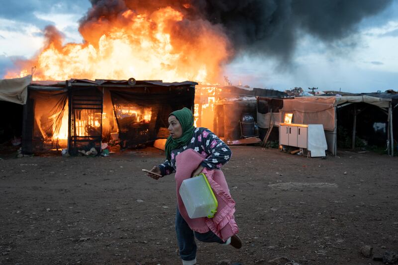 A woman flees a fire at a migrant camp in Almeria, Spain, that destroyed 100 dwellings. AP

