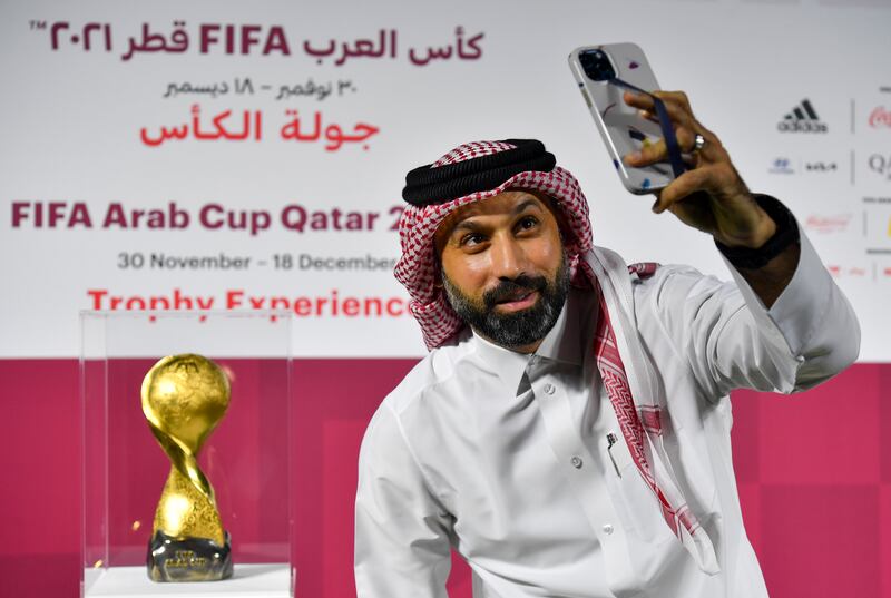 A Qatari man takes a selfie in front of the the Fifa Arab Cup Trophy.