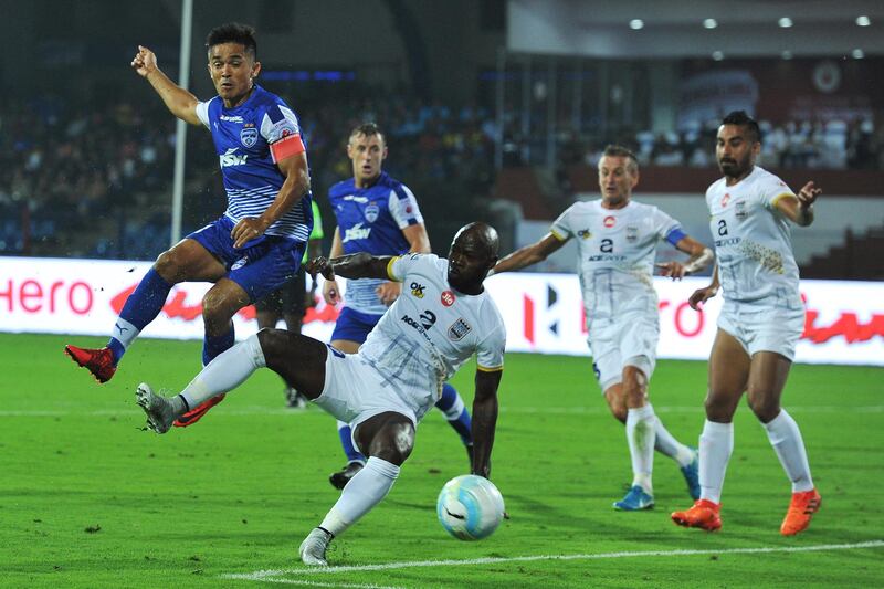 Bengaluru FC player Sunil Chhetri (L) and Mumbai City FC player Achille Emana Edzimbi (C) fight for the ball during their Indian Super League (ISL) football match at Sree Kanteerava Stadium in Bangalore on November 19, 2017. (Photo by Manjunath KIRAN / AFP) / ----IMAGE RESTRICTED TO EDITORIAL USE - STRICTLY NO COMMERCIAL USE-----