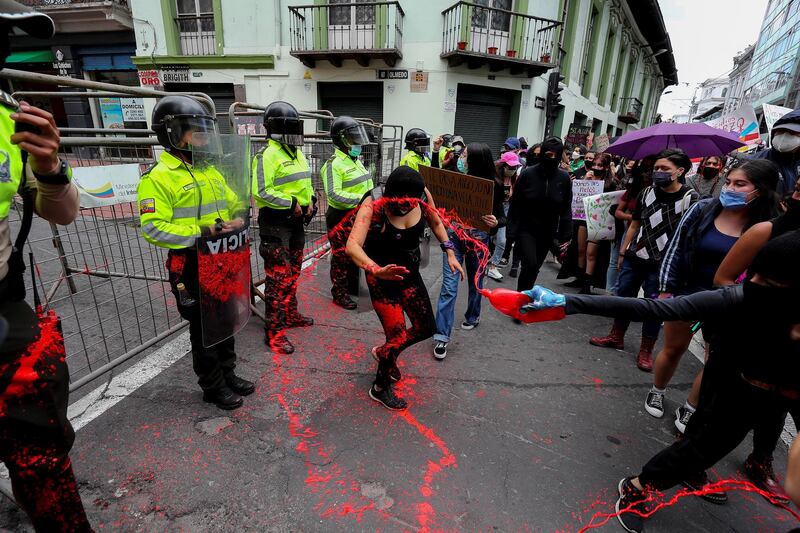 A woman spreads red paint in front of the Ecuadorian Police during a march as part of International Women's Day in Quito, Ecuador. EPA