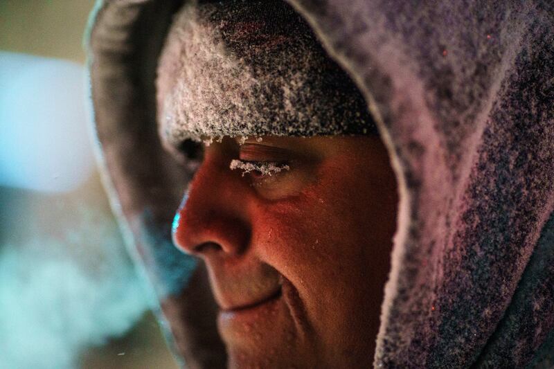 Snowflakes sit on the eyelash of resident Chris Andrade as he clears snow from a pavement in Providence. AP