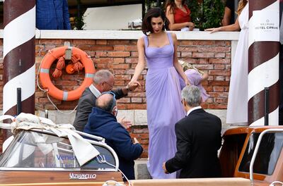 George Clooney, right, back to the camera, helps his wife Amal to board on a motorboat during the 74th edition of the Venice Film Festival, in Venice, Italy, Saturday, Sept. 2, 2017. (Ettore Ferrari/ANSA via AP)