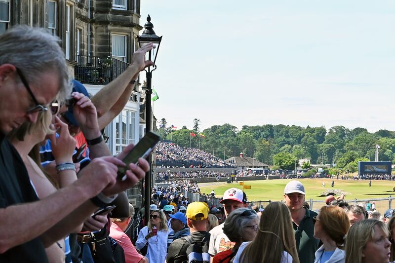 Crowds seek vantage points on fences and walls outside the ticketed area beside the 18th fairway at the 150th Open Championship golf tournament, in St Andrews, Scotland.