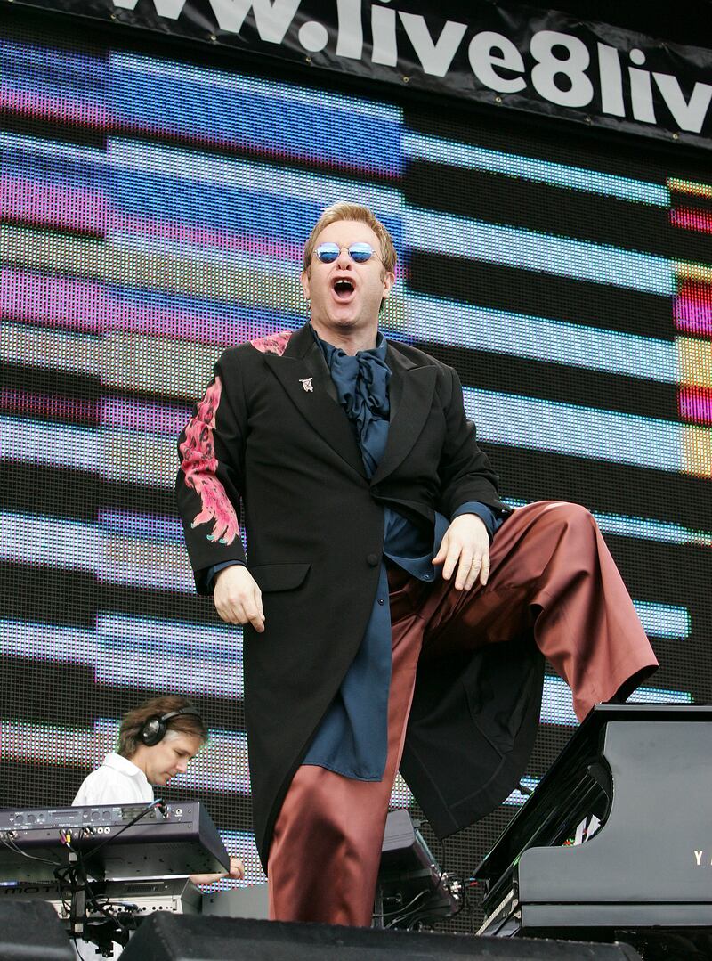 Elton John, wearing a black coat with pink, feathered pattern over a navy satin shirt and burnt orange wide-legged trousers, performs at the Live 8 London concert in Hyde Park, London on July 2, 2005. Getty Images