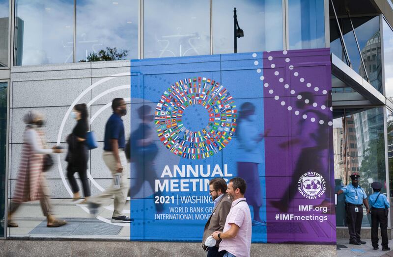 People walk past a poster announcing the annual meetings of The World Bank and International Monetary Fund (IMF) outside the IMF headquarters in Washington on October 7. The IMF extended debt relief to 24 low-income countries. AFP