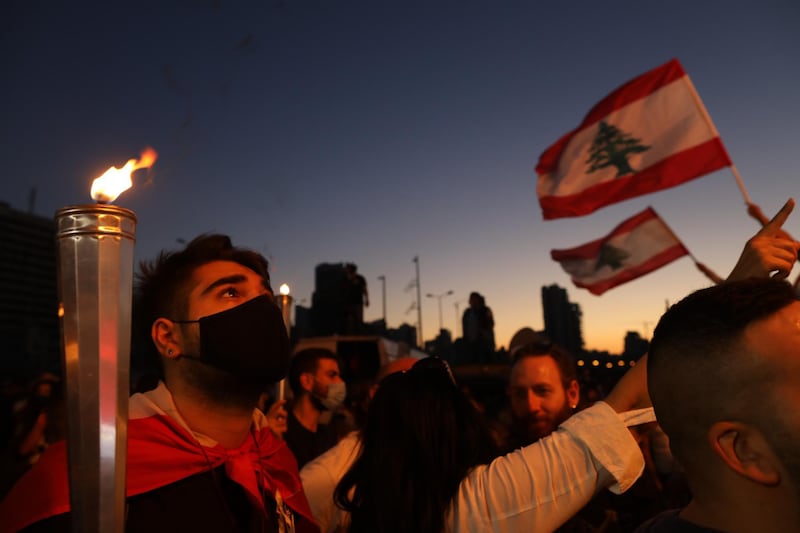 People hold Lebanese flags and lit candles to mark the first anniversary of anti-government protests. Getty Images