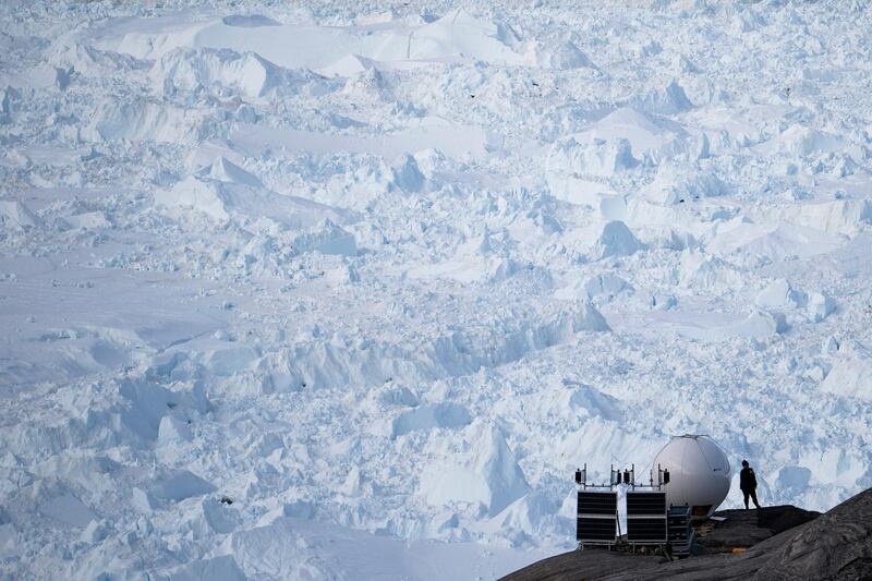 FILE - In this Aug. 16, 2019, file photo, a woman stands next to an antenna at an NYU base camp at the Helheim glacier in Greenland. Summer 2019 is hitting the island hard with record-shattering heat and extreme melt. Scientists estimate that by the end of the summer, about 440 billion tons of ice, maybe more, will have melted or calved off Greenland's giant ice sheet. U.N. Secretary-General Antonio Guterres said Tuesday at a two-day international meeting on climate change, that the coronavirus pandemic has exposed how fragile societies are, but that if governments work together on common challenges, including global warming, it can be an opportunity to 'rebuild our world for the better.' (AP Photo/Felipe Dana, File)