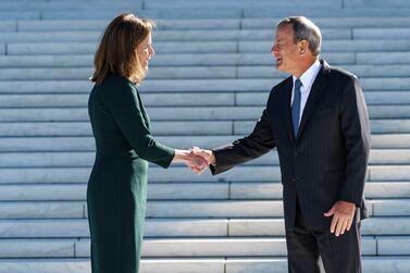 Associate Justice Amy Coney Barrett, left, shakes hands with Chief Justice of the United States John Roberts as she is escorted for a traditional investiture ceremony at the Supreme Court in Washington, Friday, Oct.  1, 2021.  Barrett, appointed by President Donald Trump, took her place on the high court in October 2020, but the COVID-19 pandemic delayed the ceremony.  (AP Photo/J.  Scott Applewhite)