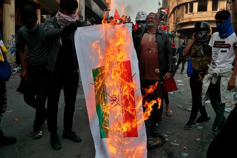 Iraqi anti-government protesters burn an Iranian flag during ongoing protests in Baghdad, Iraq. AP Photo