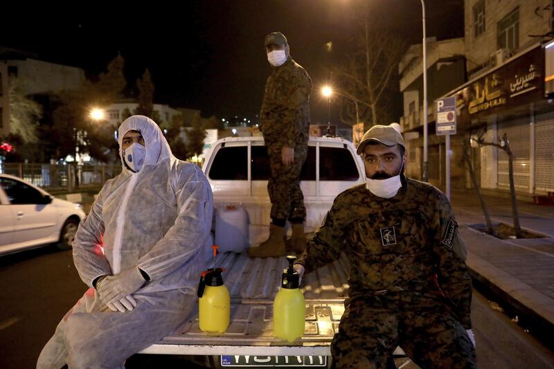 Members of Iran's Revolutionary Guard spray down streets and hospitals with disinfectants, March 4. AP