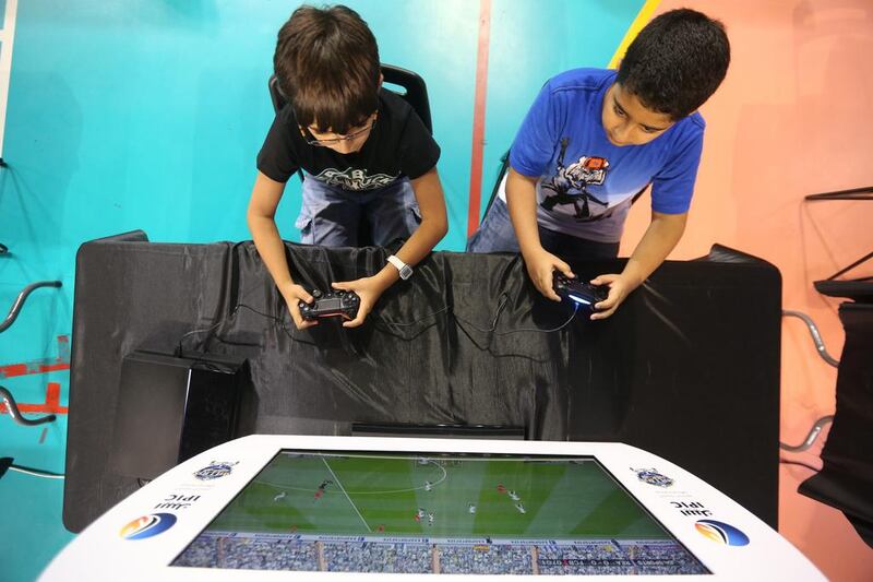 Left, Hamdan Alali, 11, and Omar Al Ali, also 11, tackle the Million Player football contest at Al Jazeera Sports Club in Abu Dhabi on Thursday. Fans follow their favourites via  monitors linked to the video games. Delores Johnson / The National 